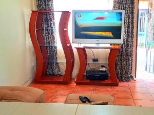 telewizor siedzący na stojaku w salonie w obiekcie Residential Inn w mieście Pretoria