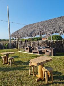 a group of picnic tables and a straw hut at Kitesurf Life Glamping in Tutóia