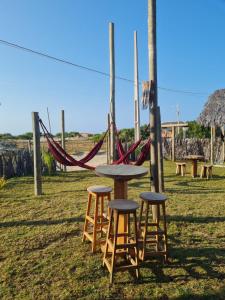 a table and stools in a field with a hammock at Kitesurf Life Glamping in Tutóia