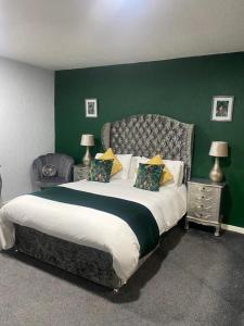 um quarto com uma cama grande e uma parede verde em Saphire Glasgow Apartments em Giffnock