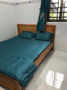 uma cama com lençóis e almofadas verdes num quarto em Khách Sạn Vinhomes Huỳnh Hotel em Ben Tre