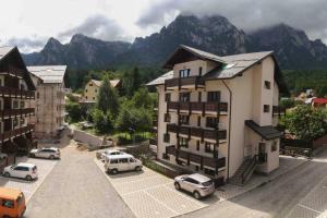 a building with cars parked in a parking lot with mountains at Mountain Valley View in Buşteni