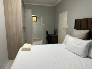uma cama branca com lençóis e almofadas brancos num quarto em Maria’s Place em Midrand