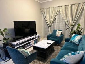 uma sala de estar com mobiliário azul e uma televisão de ecrã plano em Maria’s Place em Midrand