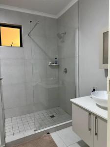 een witte badkamer met een douche en een wastafel bij Maria’s Place in Midrand