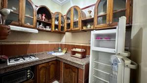 een keuken met houten kasten en een open koelkast bij Location appartement meublée Taroudant in Taroudant