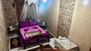 Location appartement meublée Taroudant في تارودانت: غرفة نوم صغيرة مع سرير أرجواني في غرفة