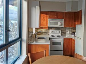 a kitchen with a stove and a microwave at Alpenglow Lodge Two Bedroom Apartment by MVA in Whistler