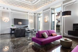 a living room with a purple couch and a kitchen at Q71 TIMELESS SUITES in Turin