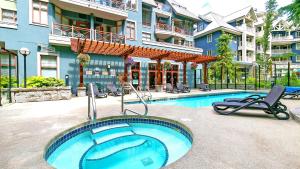 a swimming pool with chairs next to a building at Alpenglow Lodge West Coast Wonder by MVA in Whistler