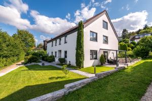 ein weißes Haus mit einem grünen Hof in der Unterkunft Ferienwohnung Blickfang am Nordberg in Goslar