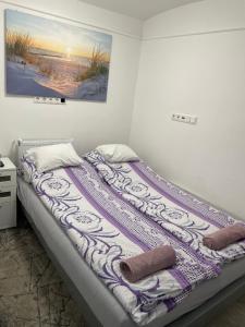 a bed with a purple and white blanket on it at Centrum Wellness Hostel in Debrecen