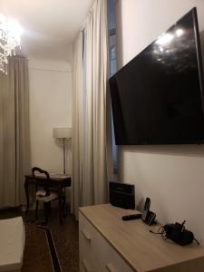 Varazze Suite Sauna e Hammam في فاراتسي: غرفة في الفندق مع تلفزيون بشاشة مسطحة كبيرة على الحائط