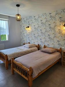 1 dormitorio con 2 camas y pared con papel pintado en Gîte Cadet rousselle, en Lessay