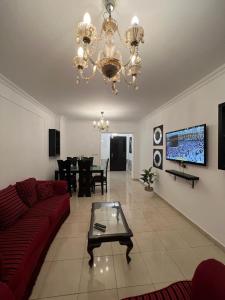 a living room with a red couch and a chandelier at Madinaty, Elite new apartment with garden in Madinaty