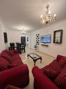 a living room with two red couches and a table at Madinaty, Elite new apartment with garden in Madinaty