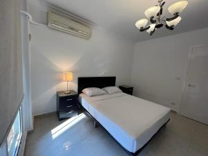 a white bedroom with a bed and a lamp at Madinaty, Elite new apartment with garden in Madinaty