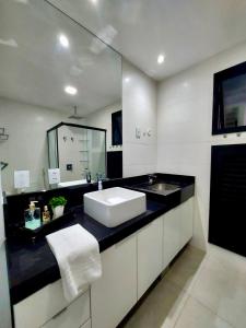 a bathroom with a sink and a large mirror at Uma Linda Vista com Quarto Privativo no Ed. Vertigo in Campo Grande