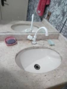 a bathroom counter with a sink with a toothbrush and a toothbrush at Alugo quarto, próximo à praia in Torres