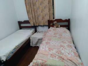 a bedroom with two beds with a teddy bear sitting on them at Alugo quarto, próximo à praia in Torres