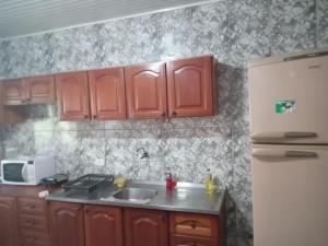 Il comprend une cuisine équipée de placards rouges et d'un réfrigérateur blanc. dans l'établissement Alugo quarto, próximo à praia, à Torres