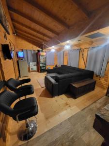 - un salon avec un canapé noir et des chaises dans l'établissement Vikendica Chalet Nišići, à Ilijaš