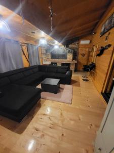 a living room with a black couch and a table at Vikendica Chalet Nišići in Ilijaš
