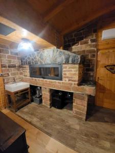a stone fireplace with a tv in a room at Vikendica Chalet Nišići in Ilijaš