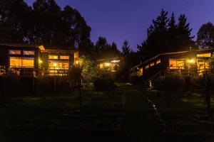 un par de casas por la noche con luces en Cabañas Bosques de Puertecillo, en Puertecillo