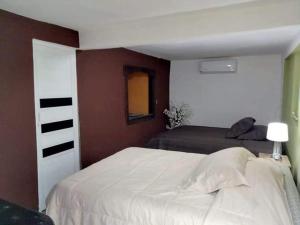 a bedroom with a white bed and a brown wall at Hotel y Cabaña La Peña in Xilitla