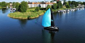 a sail boat with a blue sail on the water at Marina Relax - widok na jezioro, parking podziemny, winda, Netflix, TV55" in Iława