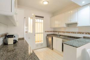 eine große Küche mit weißen Schränken und einem Waschbecken in der Unterkunft Villa Mariposa in Orihuela