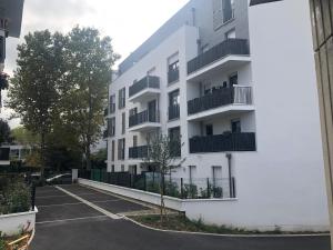 a white apartment building with a parking lot at Grande chambre avec salle de bain privative à Nanterre Préfecture proche La Défense Aréna Campus SNCF et Paris in Nanterre