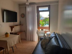 een woonkamer met een bank, een tafel en een raam bij Apart. aconchegante, 100 m da praia. in Porto Seguro