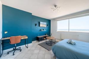 - une chambre avec un mur bleu, un bureau et un lit dans l'établissement *Face à la mer* Malo-les-bains, à Dunkerque