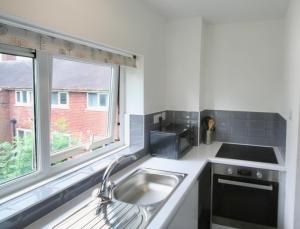 eine Küche mit einem Waschbecken und einem Fenster in der Unterkunft Sheffield serviced apartment in Greenhill