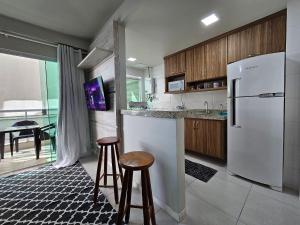 a kitchen with a white refrigerator and two stools at AP encantador na Praia do Forte! Porto Azul (107) in Cabo Frio