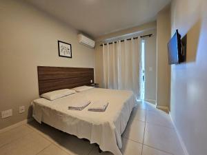 a bedroom with a large bed with a tv on the wall at AP encantador na Praia do Forte! Porto Azul (107) in Cabo Frio