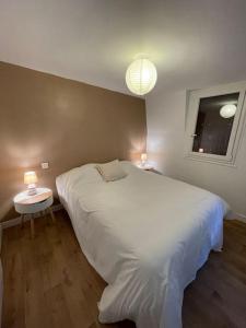 1 Schlafzimmer mit einem großen weißen Bett und 2 Tischen in der Unterkunft Maison Hyper Centre Brive in Brive-la-Gaillarde