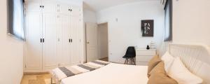 Un dormitorio blanco con una cama y una silla. en Moderno Apartamento junto a la Playa, en Sanlúcar de Barrameda 19 fotos más