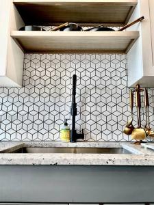 a kitchen with a sink and a white tiled wall at West Midtown Jewel in Atlanta