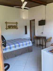 sypialnia z łóżkiem, biurkiem i telewizorem w obiekcie Recanto Primavera w mieście Boiçucanga