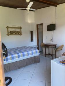 a bedroom with a bed and a desk and a television at Recanto Primavera in Boicucanga
