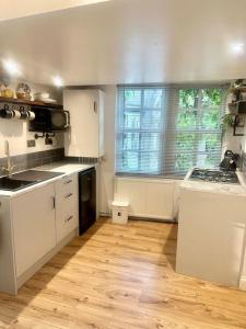 a kitchen with white appliances and a wooden floor at Cosy Stylish Studio Apartment in Trowbridge