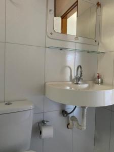een badkamer met een wastafel, een toilet en een spiegel bij Recanto Primavera in Boicucanga