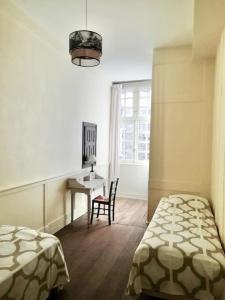 1 dormitorio con 2 camas, escritorio y ventana en Appartement Intra-Muros - 2 chambres en Saint-Malo