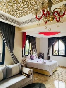1 dormitorio con cama, sofá y lámpara de araña en Villa Aïcha, en Marrakech