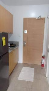 a kitchen with a refrigerator and a wooden door at Minimalist Condo Studio City Tower 2 Filinvest Alabang Muntinlupa in Manila