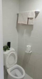 a white bathroom with a toilet with a plant on it at Minimalist Condo Studio City Tower 2 Filinvest Alabang Muntinlupa in Manila