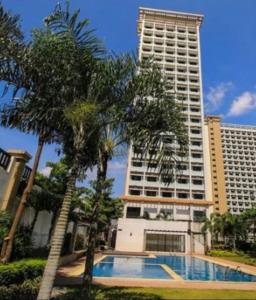 a swimming pool in front of a tall building at Minimalist Condo Studio City Tower 2 Filinvest Alabang Muntinlupa in Manila
